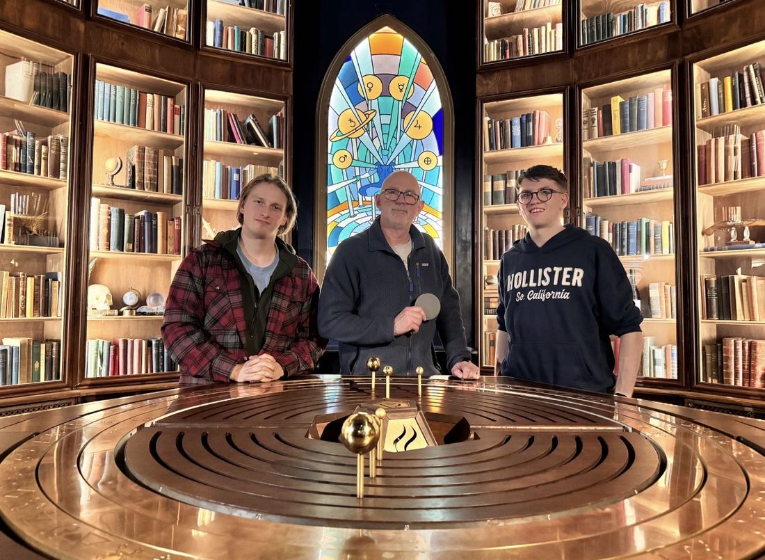 Viktor and teammates beside a giant orrery in a library escape room